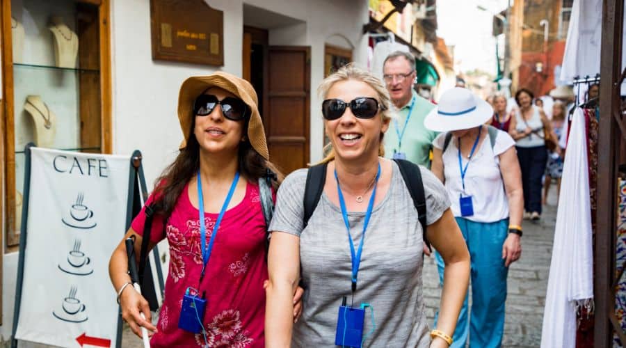 Guia caminhando por uma rua estreita mostrando a cidade para os turistas que estão feliz ouvindo as histórias sobre o lugar