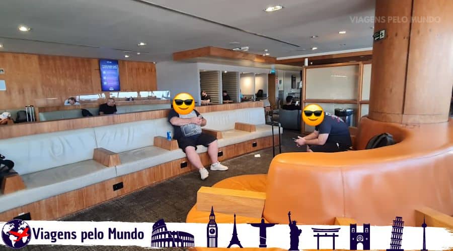Lounge da Gol Nacional. Bancos e sofá com passageiros aguardando o voo.