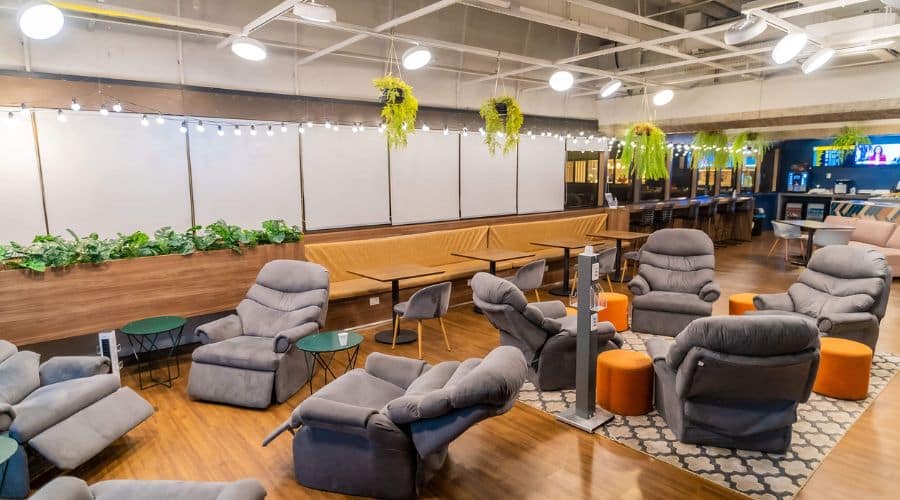 Urban Lounge Guarulhos. Espaço com várias poltronas reclináveis com balcão com vista para a pista do Aeroporto.
