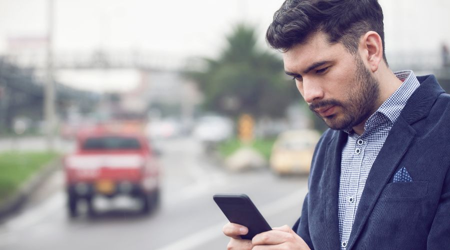 Pedindo um Uber no Aeroporto de Santiago. Homem segurando o celular enquanto aguarda seu motorista