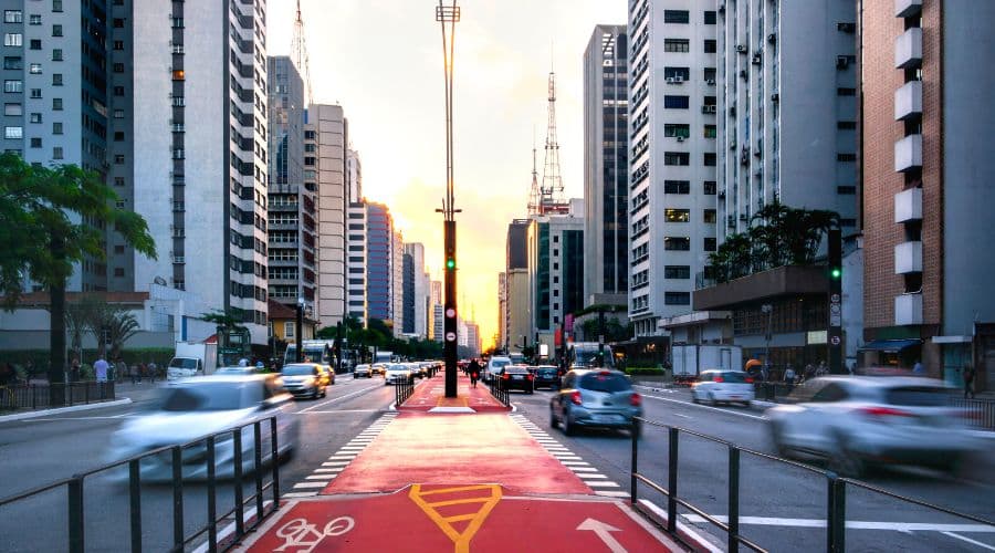 Avenida Paulista em São Paulo. Faixa de ciclistas no meio e as faixas de carros cercadas dos prédios