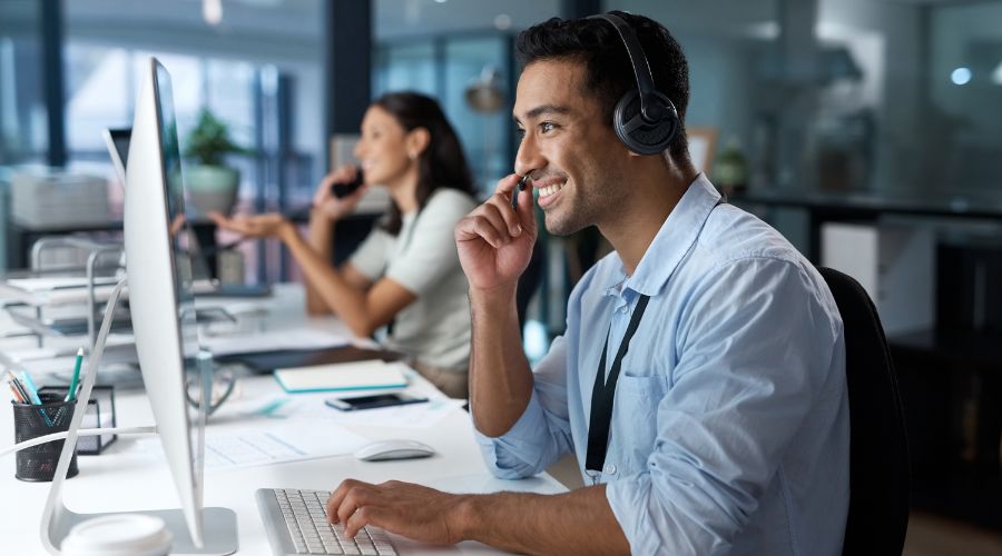 Equipe de atendimento online da empresa. Dois analistas sorrindo na frente do computador com headset na cabeça