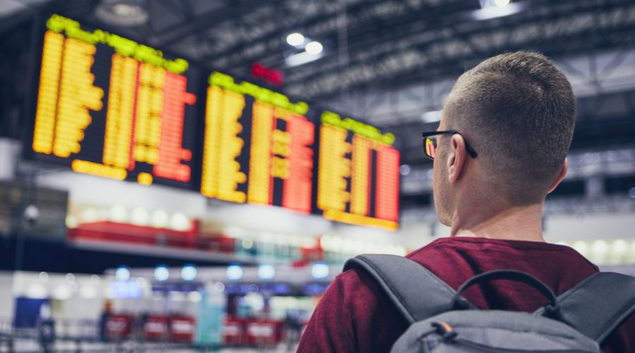 Homem olhando o painel de voos no aeroporto.
