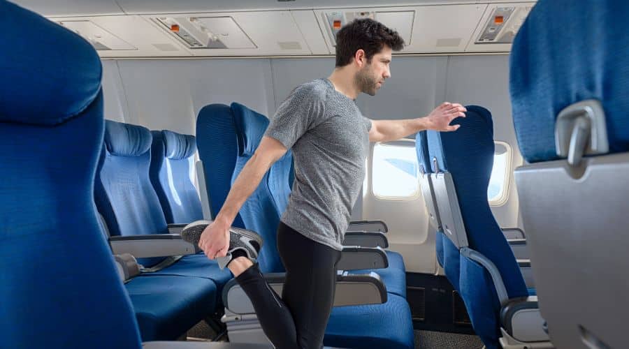 Dicas para evitar o Jet Lag. Homem se alongando no corredor do avião