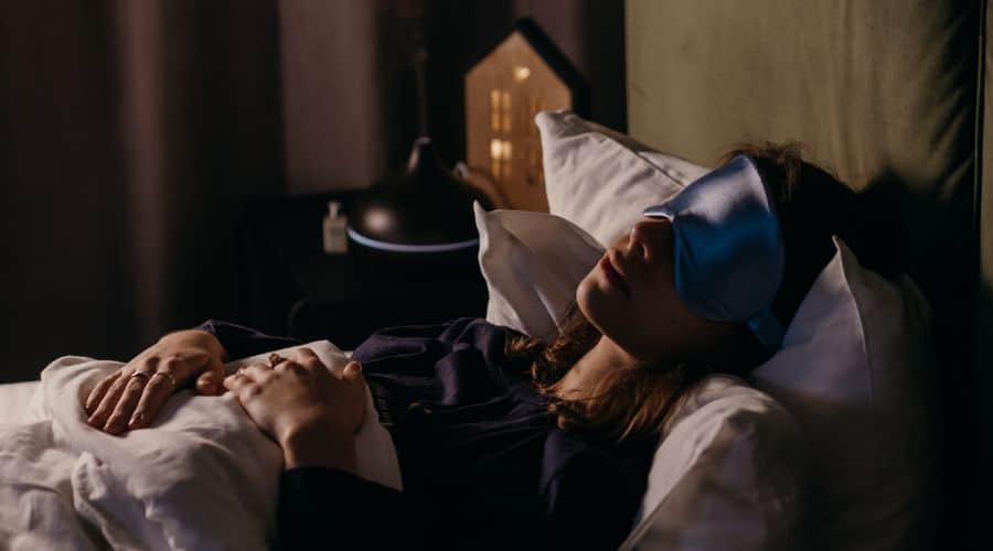 Mulher deitada na cama com uma máscara de dormir