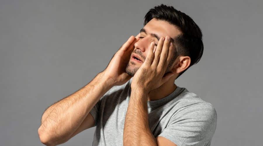 Homem com dor de cabeça com as mãos na cabeça de dor