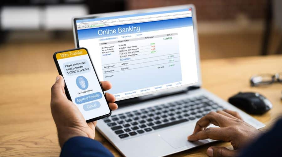 Cuidados ao transferir dinheiro na Remessa Online. Pessoa com o notebook e celular efetuando uma transferência internacional