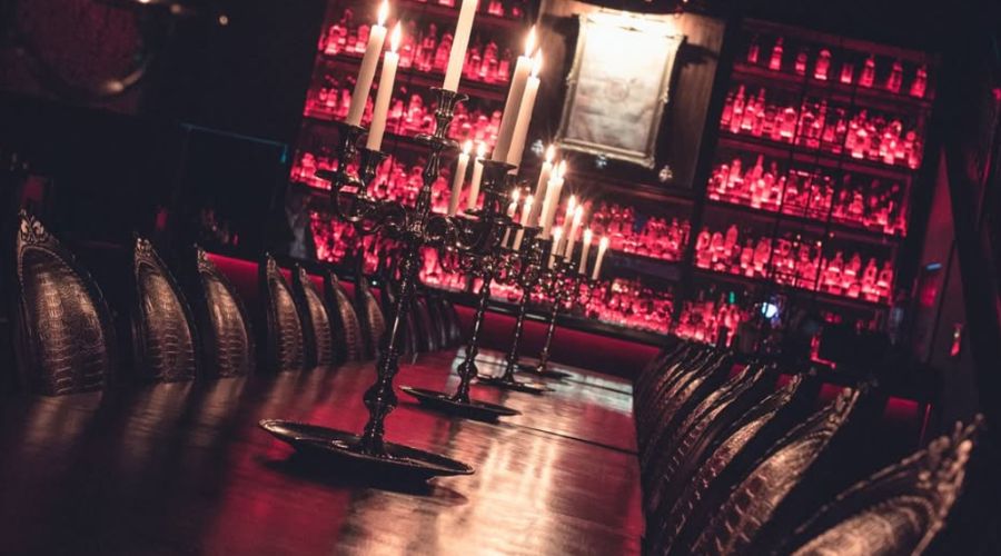 Interior do El Purgatório Bar com decoração mística, incluindo candelabros e leituras de tarô.